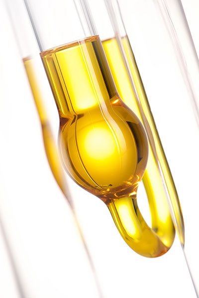 Nahaufnahme von drei Glasröhren mit goldenem, klaren Flüssigkeitsfüllstand vor weißem Hintergrund