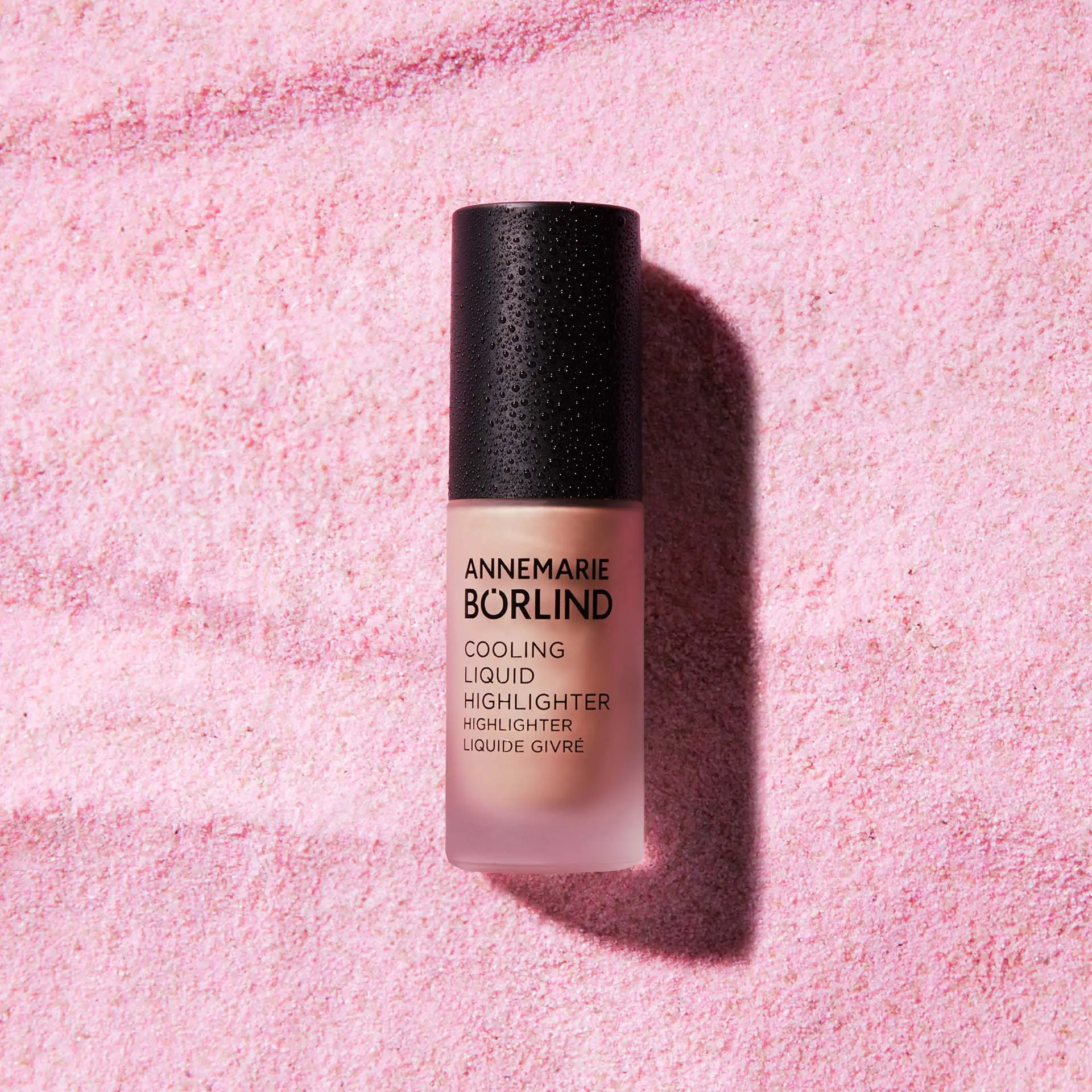 ANNEMARIE BÖRLIND Cooling Liquid Highlighter Flakon mit schwarzem Deckel auf rosa Hintergrund