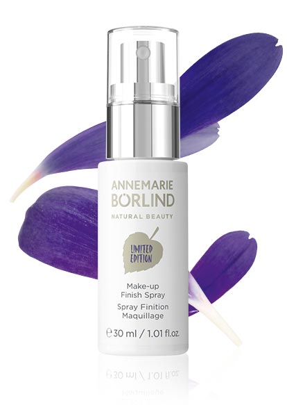 ANNEMARIE BÖRLIND Make-up Finish Spray 30 ml, Limited Edition, mit violetten Blütenblättern im Hintergrund