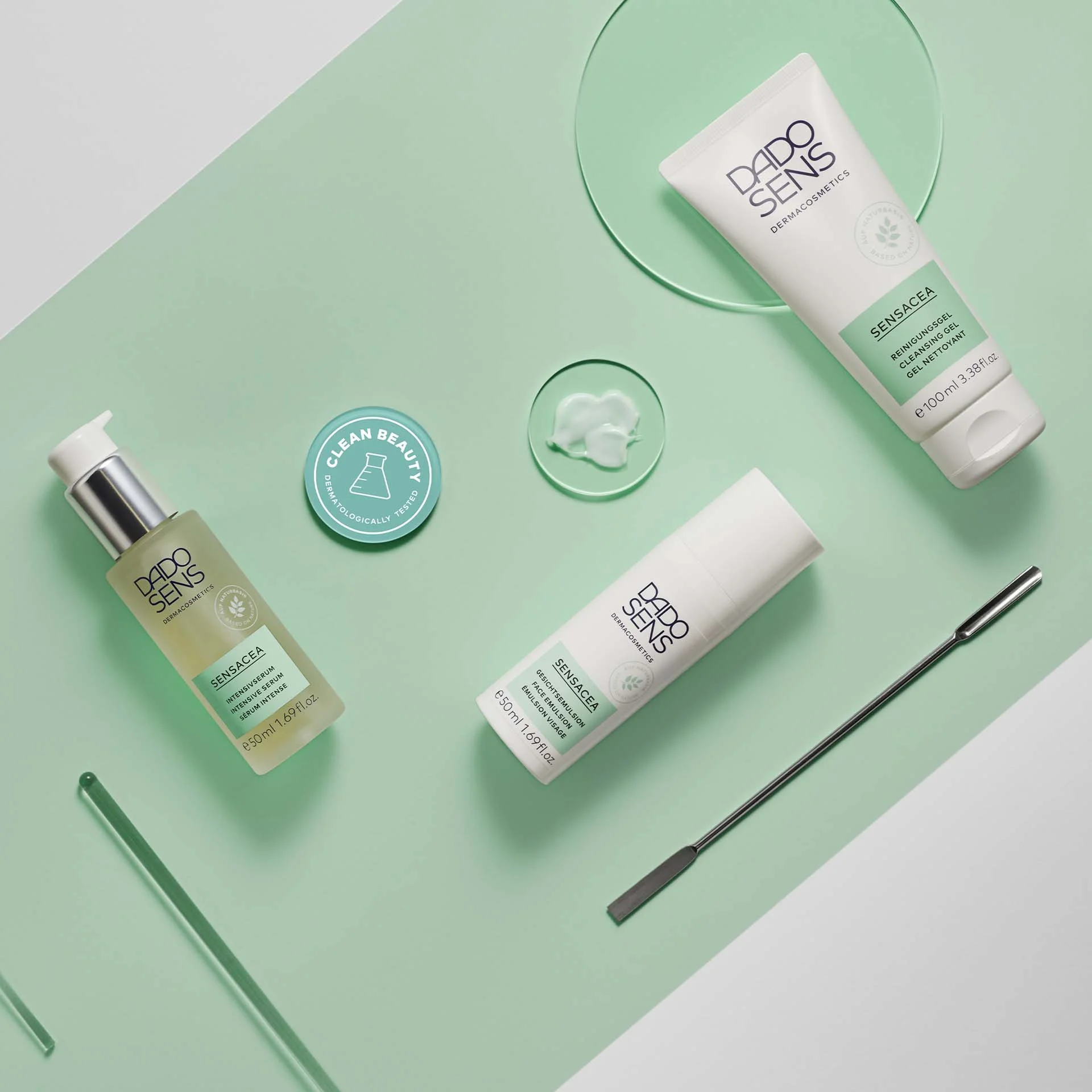 DADO SENS SENSACEA Serum, Gesichts-Emulsion und Reinigungsgel auf grünem Hintergrund mit Produktprobe