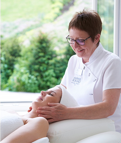 Kosmetikerin führt im NATURAL BEAUTY SPA eine entspannende Gesichtsbehandlung bei liegender Kundin durch