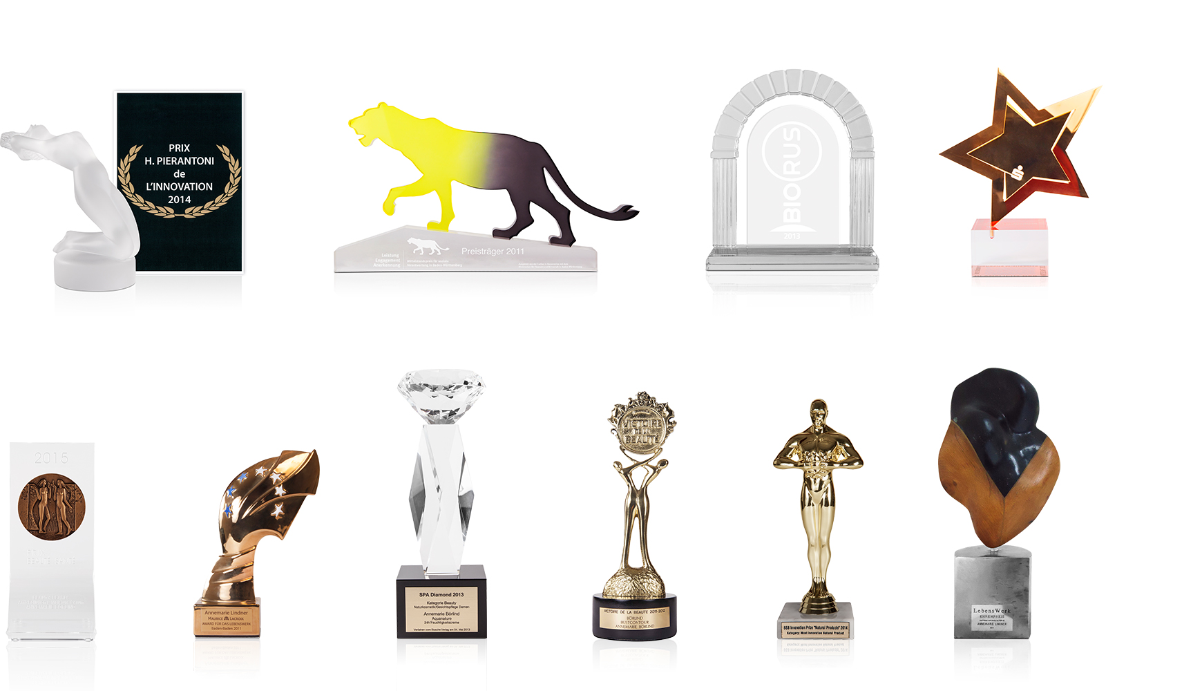 Zehn verschiedene Auszeichnungen und Trophäen aus Glas, Metall und Holz auf weißem Hintergrund