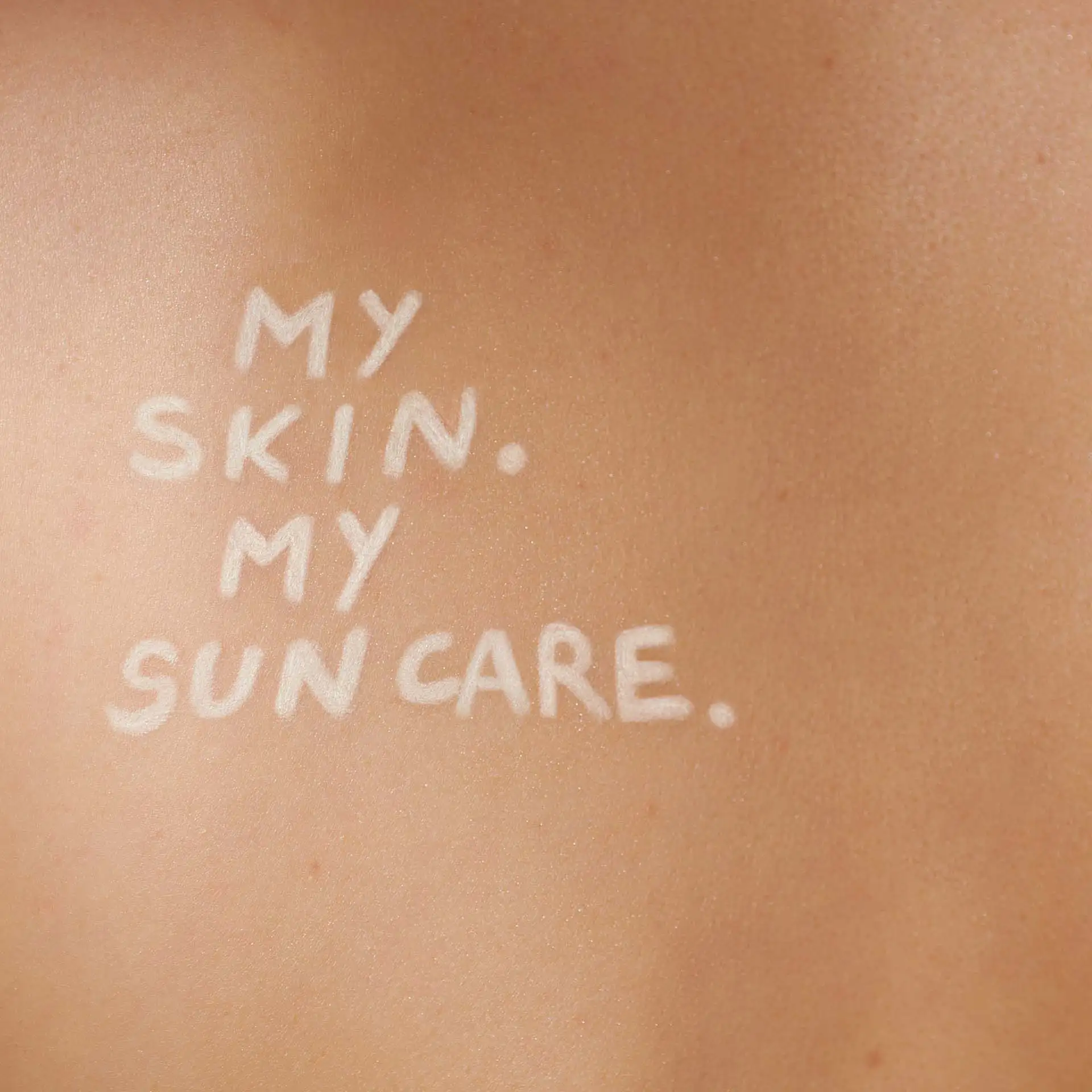Schriftzug "MY SKIN. MY SUN CARE." in weißer Creme auf gebräunter Hautoberfläche