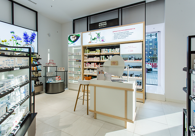 Heller Verkaufsraum mit ANNEMARIE BÖRLIND Naturkosmetik-Regalen, Theke mit Spiegel und Hocker, Tageslicht