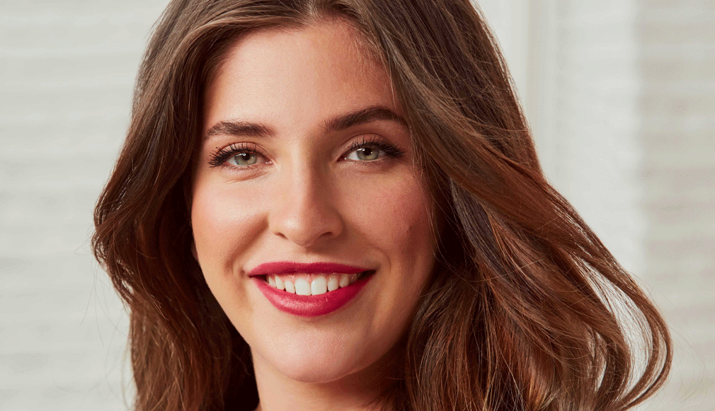Nahaufnahme eines lächelnden Models mit roten Lippen und natürlichem Make-up vor hellem Hintergrund