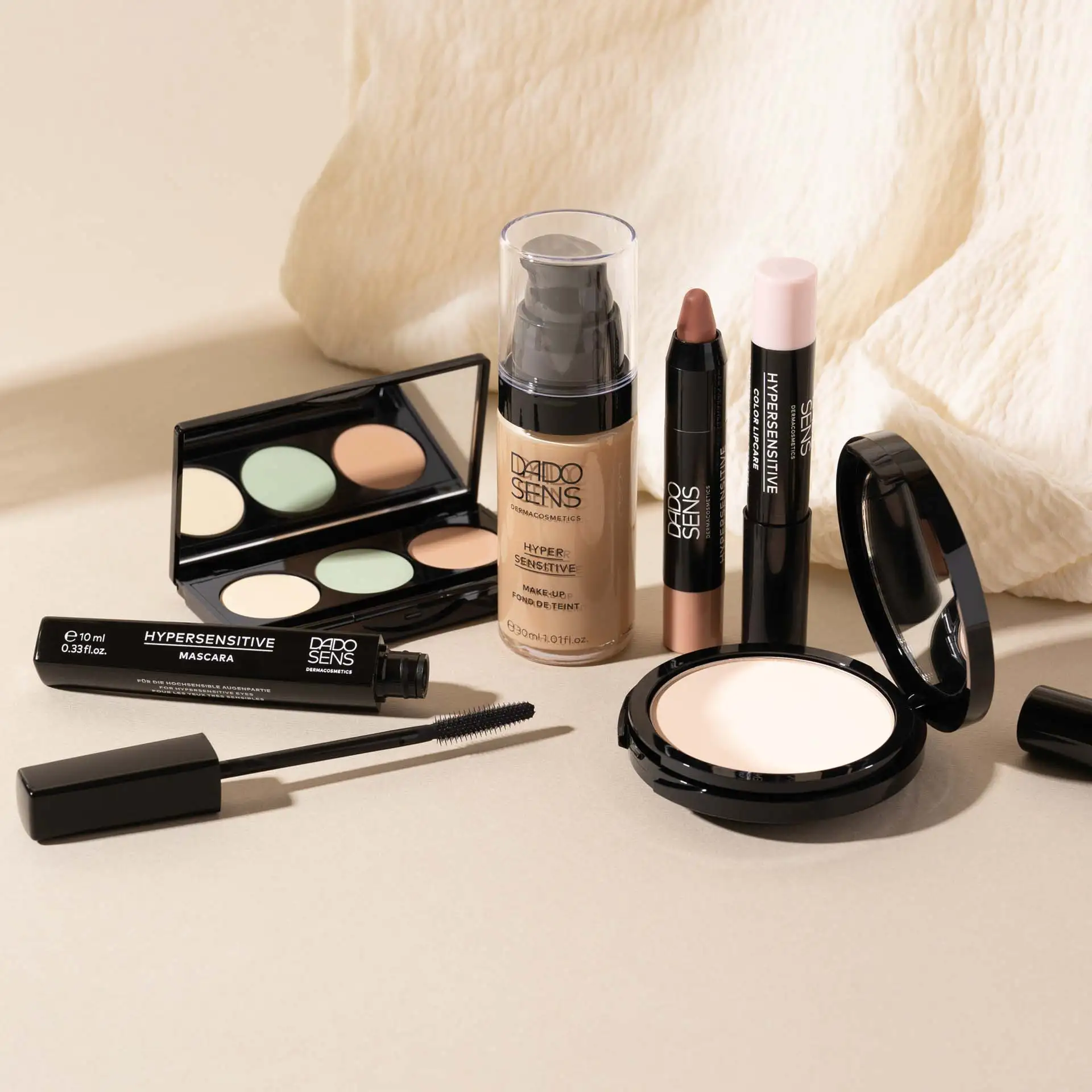 DADO SENS HYPERSENSITIVE Make-up mit Mascara, Foundation, Concealer, Lippenstift und Puder auf hellem Untergrund