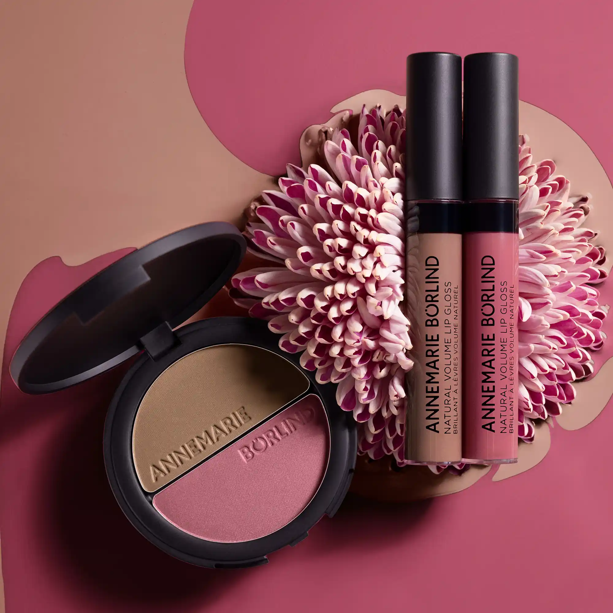 ANNEMARIE BÖRLIND NATURAL HUG SET mit 2IN1 BRONZER & SOFT BLUSH sowie NATURAL VOLUME LIP GLOSS in Farben Nude Hug und Snuggle Berry, dekorativ auf Blüte vor braun-pinkem Hintergrund inszeniert