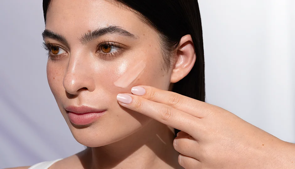 Mikrobiom der Haut Frau trägt mit zwei Fingern eine Creme auf die Wange auf, natürliche Haut im Tageslicht sichtbar