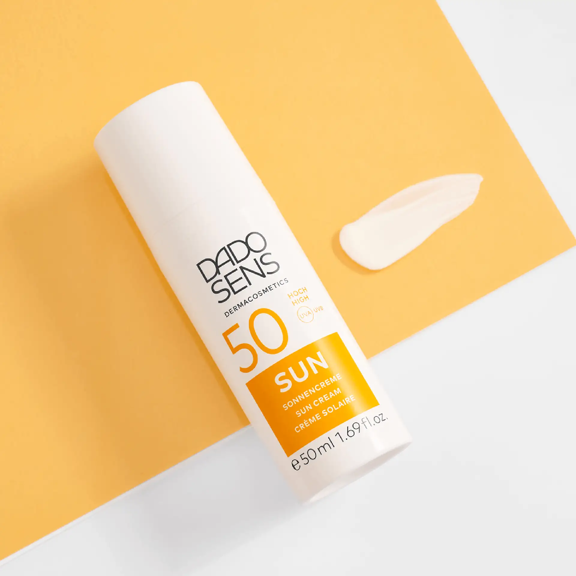 DADO SENS SUN Sonnencreme SPF 50 in 50 ml Tube mit Cremeprobe auf gelbem Hintergrund