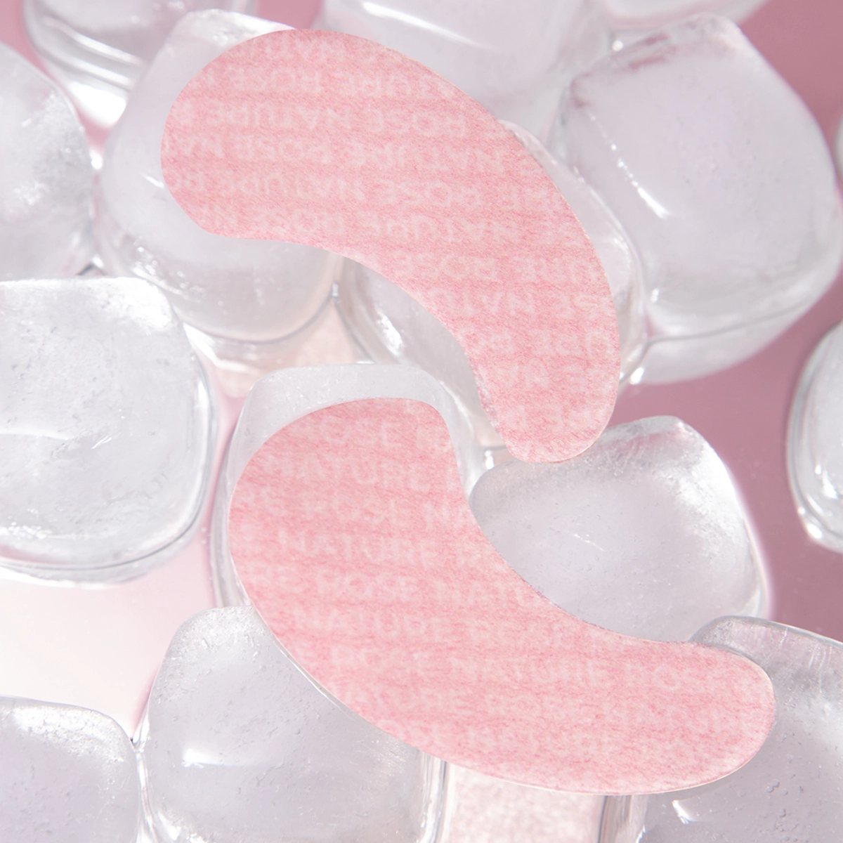 Zwei rosa Augenpads auf Eiswürfeln, die kühlende Pflege und Erfrischung symbolisieren