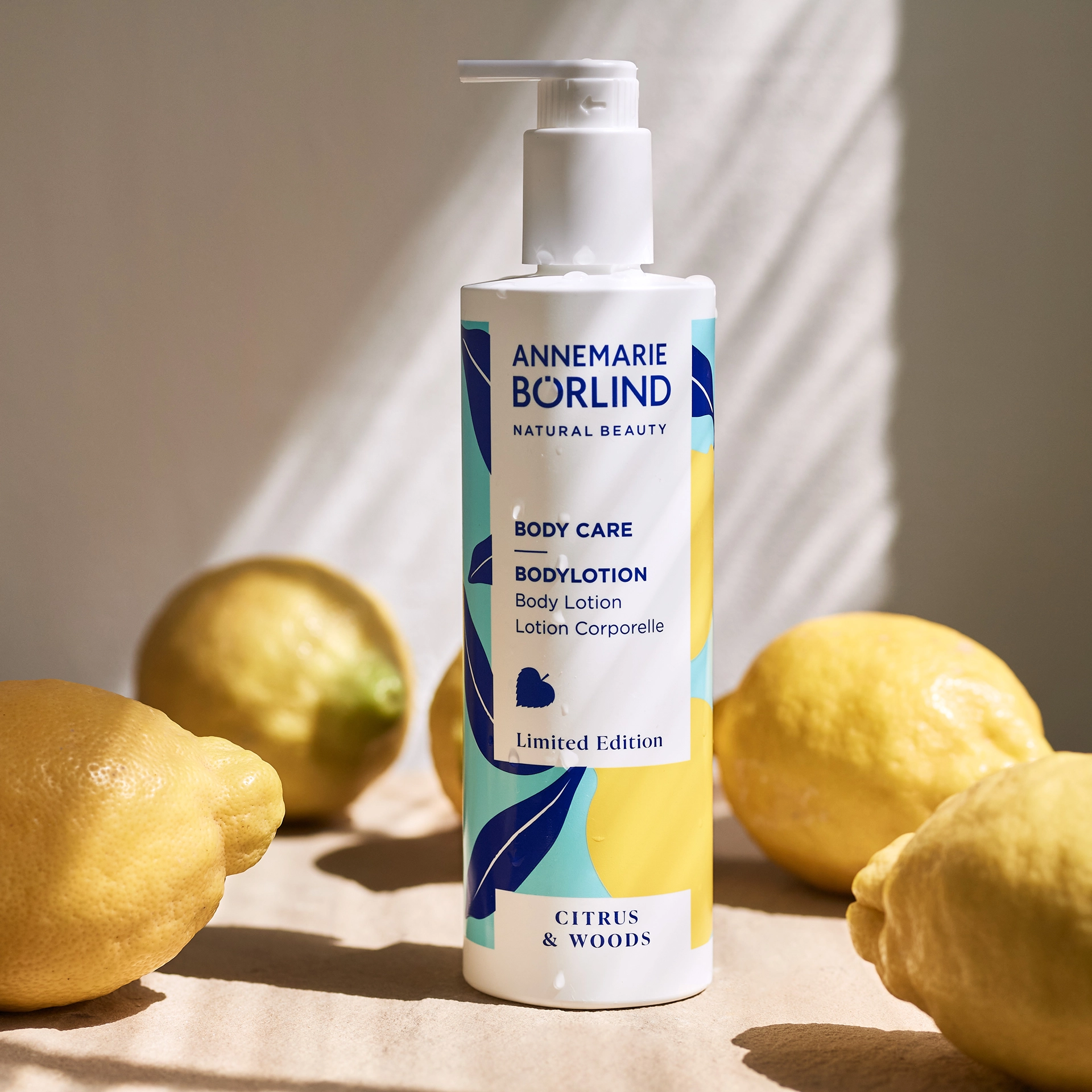 ANNEMARIE BÖRLIND Bodylotion Citrus & Woods in weißem Spender umgeben von Zitronen, Limited Edition