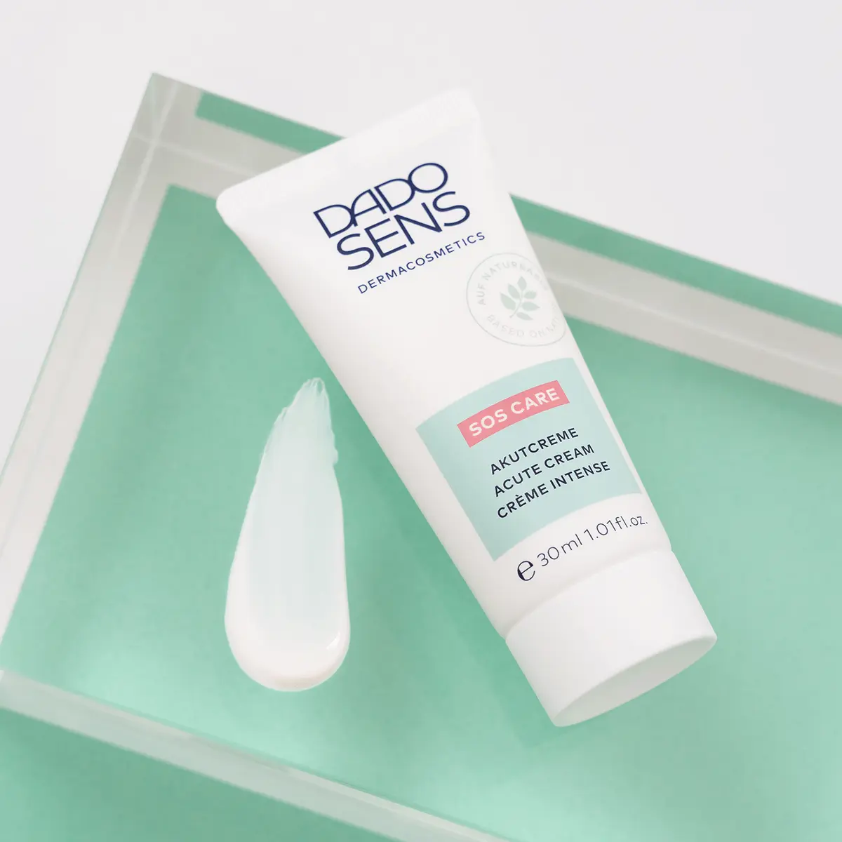 DADO SENS SOS CARE Akutcreme 30 ml Tube mit Cremeprobe auf grünem Untergrund