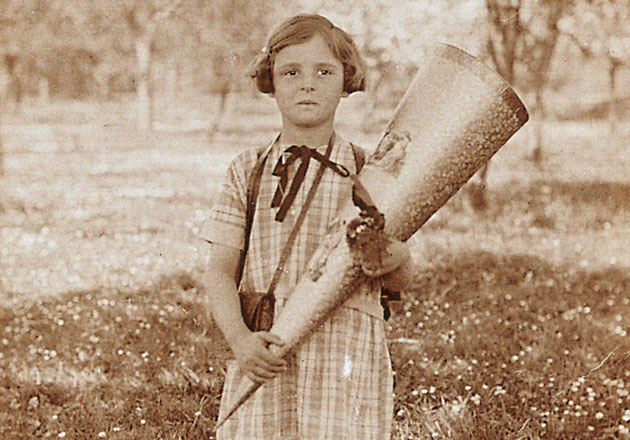 Annemarie Lindner als Kind in kariertem Kleid hält große Schultüte im Freien, sepiafarbene Aufnahme