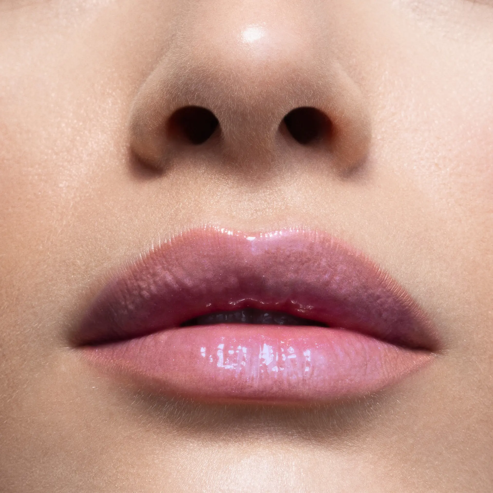 Glänzende Lippen mit zartem, lavendelfarbenem Lipgloss auf heller Haut, Nahaufnahme Mundbereich
