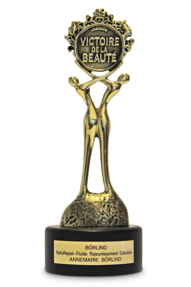 Goldfarbene Trophäe mit zwei stilisierten Figuren und Schriftzug "Victoire de la Beauté", Sockel mit ANNEMARIE BÖRLIND-Pla...