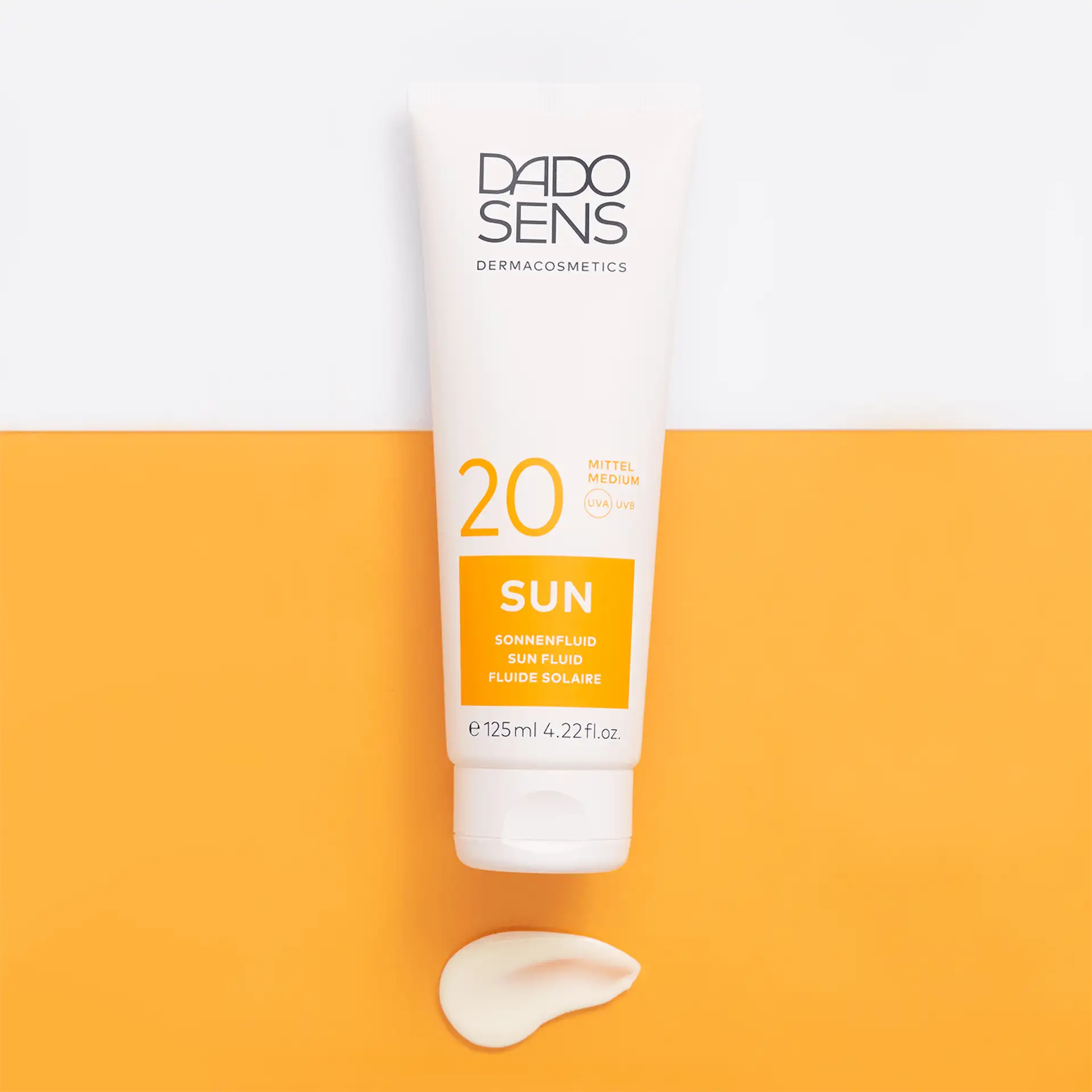 DADO SENS SUN Sonnenfluid SPF 20 in 125 ml Tube mit Cremeprobe auf orange-weißem Hintergrund
