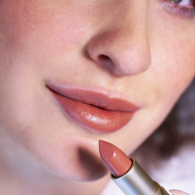 Nahaufnahme von Lippen mit matter, pfirsichfarbener Lippenstiftfarbe, Lippenstift wird gerade aufgetragen