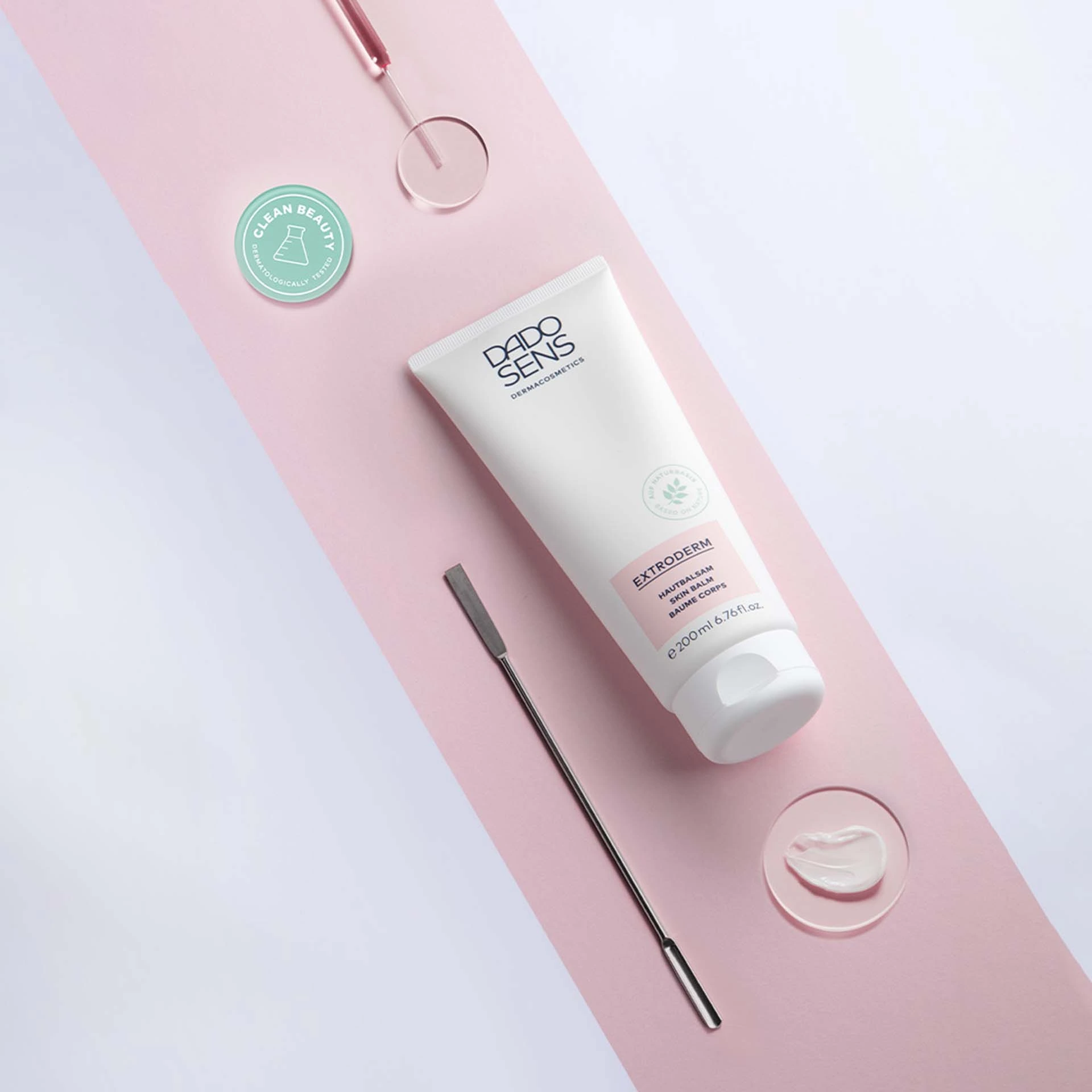 DADO SENS EXTRODERM Hautbalsam 200 ml auf rosa Untergrund mit Cremeprobe und Spatel