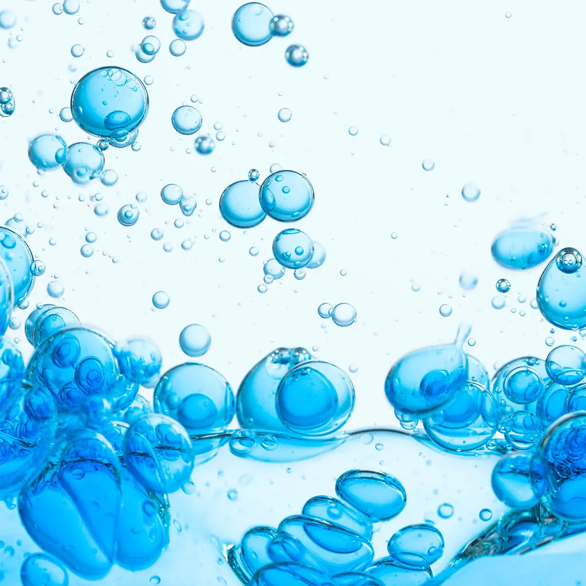 Blau schimmernde Blasen in klarem Wasser vor hellem Hintergrund, Nahaufnahme flüssiger Textur