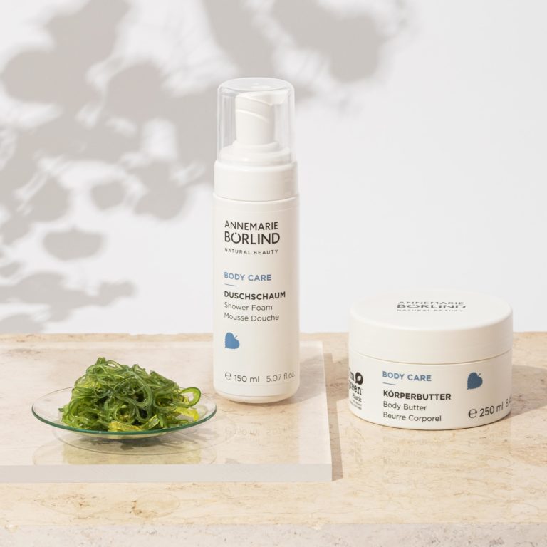ANNEMARIE BÖRLIND BODY CARE Duschschaum 150 ml und Körperbutter 250 ml auf hellem Untergrund mit Algenblatt