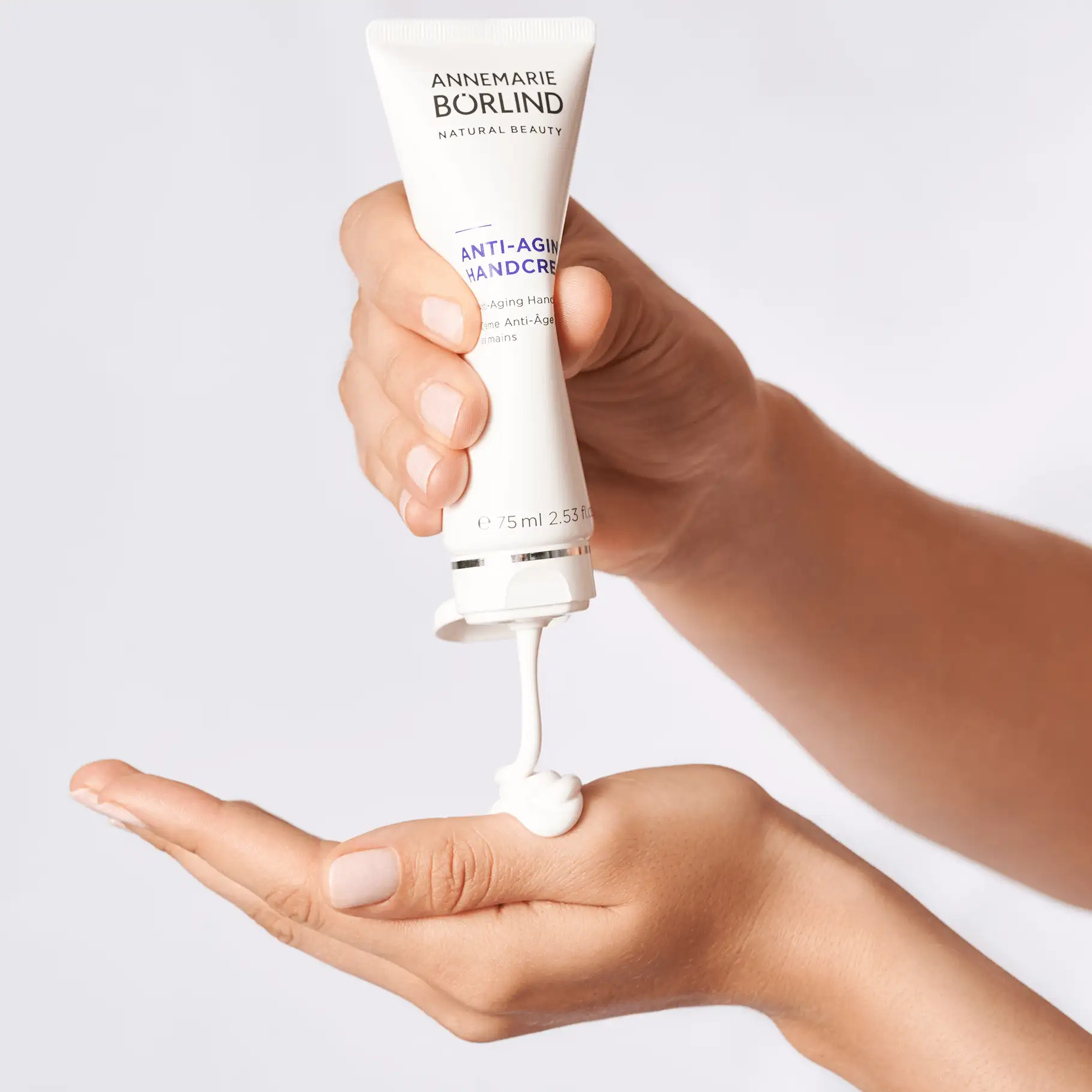 ANNEMARIE BÖRLIND Anti-Aging Handcreme wird aus Tube auf Handfläche gedrückt, weiß und cremig