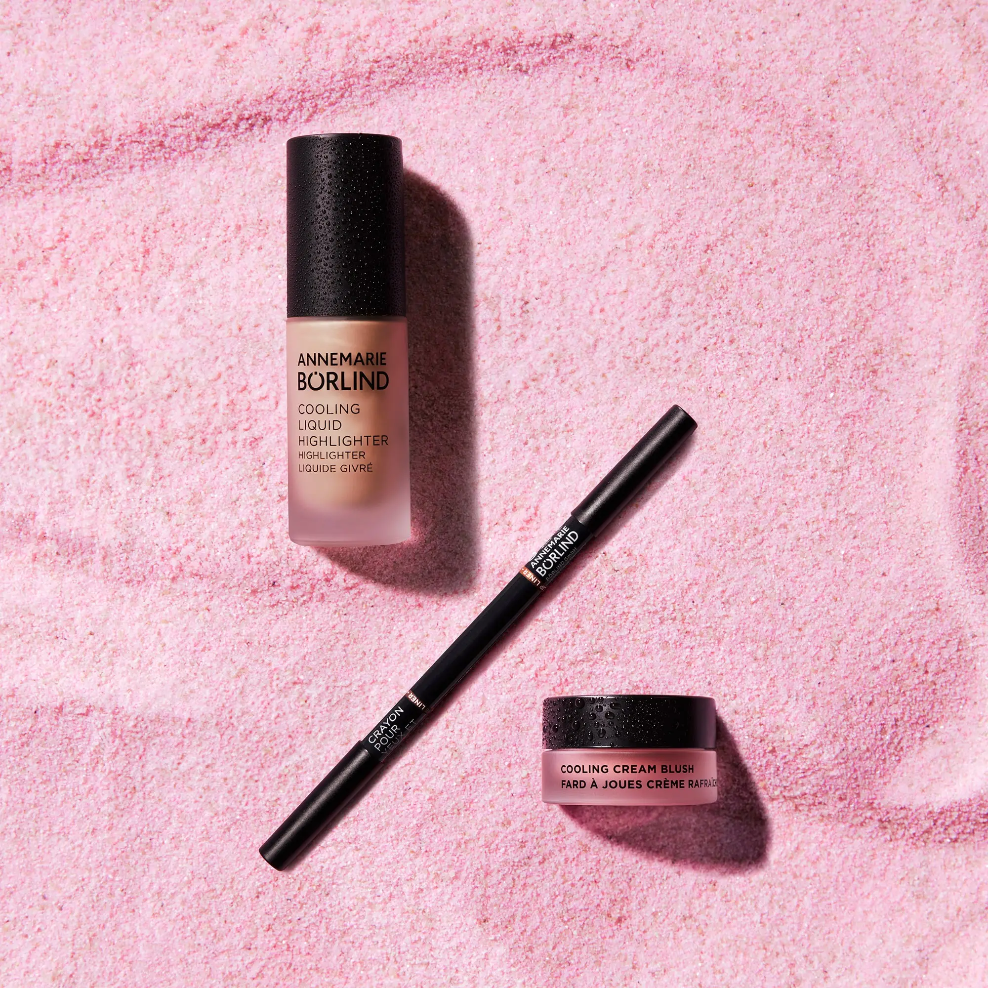 ANNEMARIE BÖRLIND Cooling Liquid Highlighter, Eyelinerstift und Cooling Cream Blush auf rosa Untergrund
