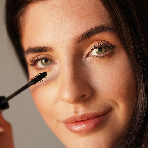 Nahaufnahme einer Frau, die ANNEMARIE BÖRLIND Volumen-Mascara auf ihre Wimpern aufträgt, natürlicher Look