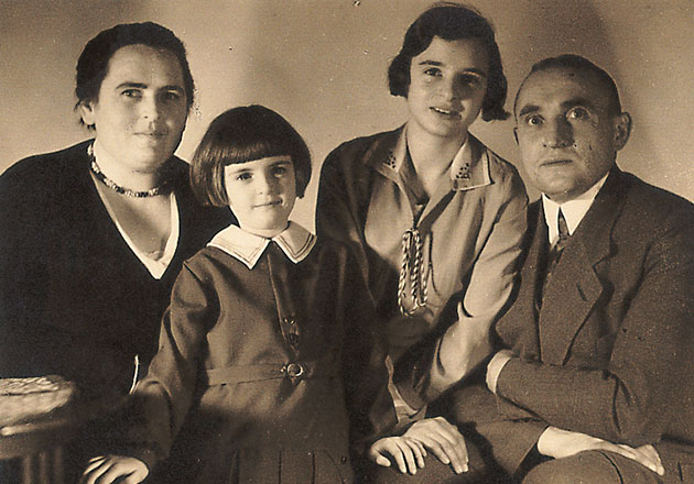 Vier Personen sitzen eng nebeneinander, zwei Erwachsene und zwei Kinder, in einem Schwarz-Weiß-Foto.