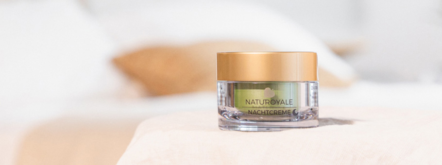 ANNEMARIE BÖRLIND NATUROYALE Nachtcreme im transparenten Tiegel mit goldenem Deckel auf hellem Stoffhintergrund