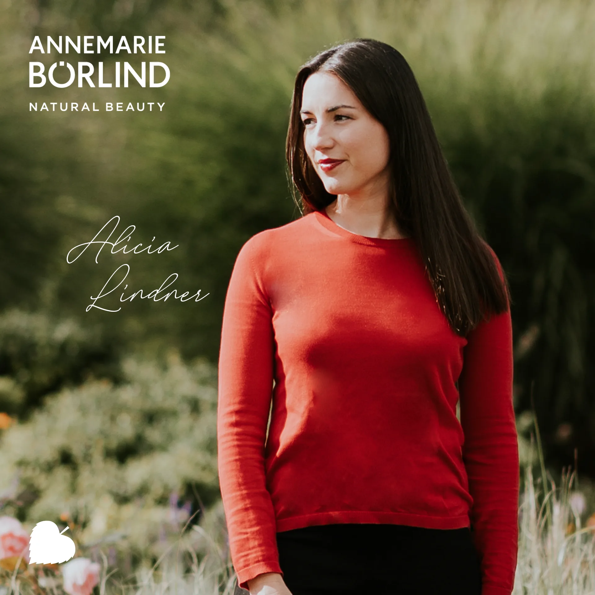 Frau mit rotem Pullover steht im Grünen und blickt nach rechts, ANNEMARIE BÖRLIND Logo oben links