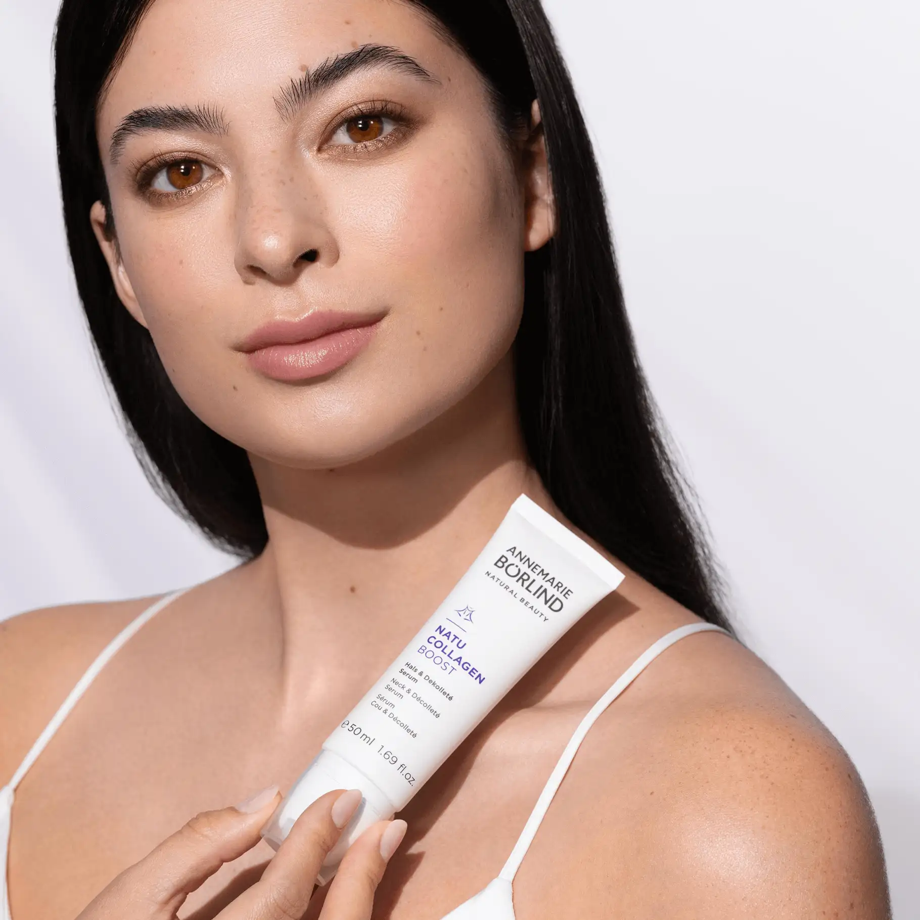 Frau hält ANNEMARIE BÖRLIND NATU COLLAGEN BOOST Serum für Hals und Dekolleté in weißer Tube