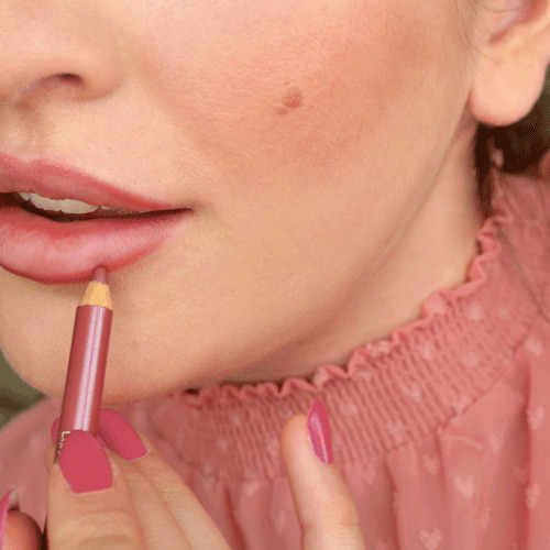 Lippenkonturenstift in Rosé wird auf die Lippen eines Models mit rosafarbenem Oberteil aufgetragen