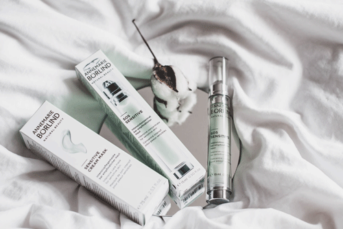 ANNEMARIE BÖRLIND SENSITIV CREAM & SOS SENSITIVE Serum mit Spender auf weißem Stoff und Baumwollzweig
