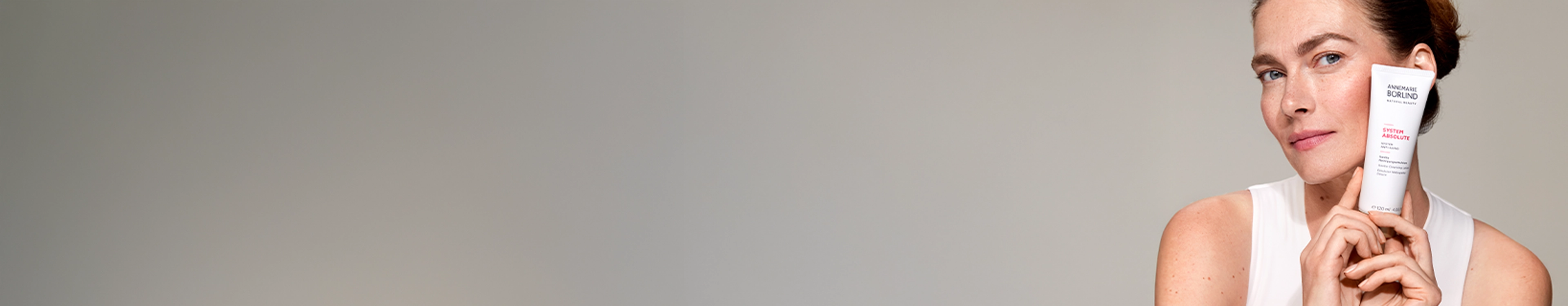 Frau mit SYSTEM ABSOLUTE Reinigungsemulsion neben Gesicht abgebildet