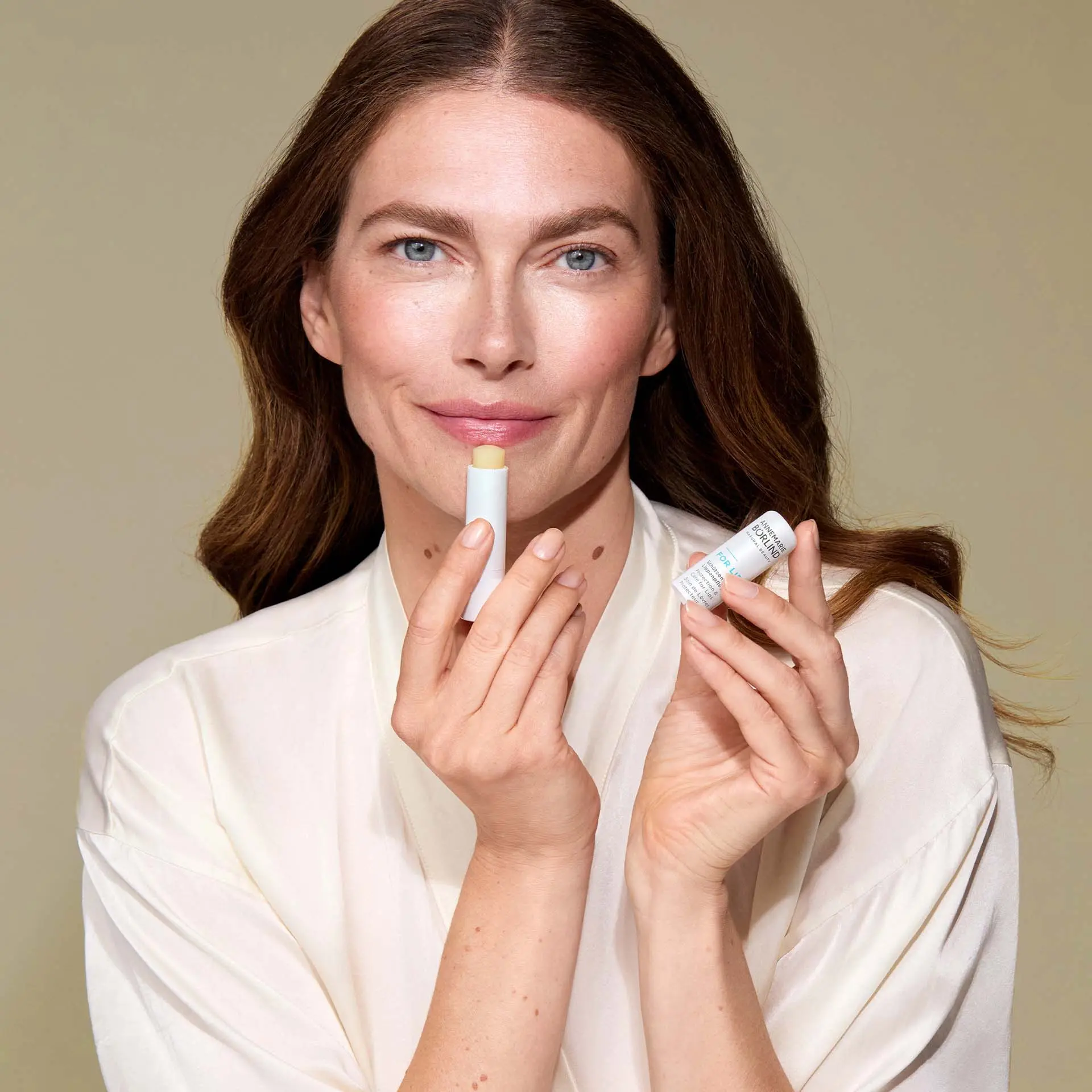 ANNEMARIE BÖRLIND FOR LIPS in der Hand einer Frau vor beigem Hintergrund