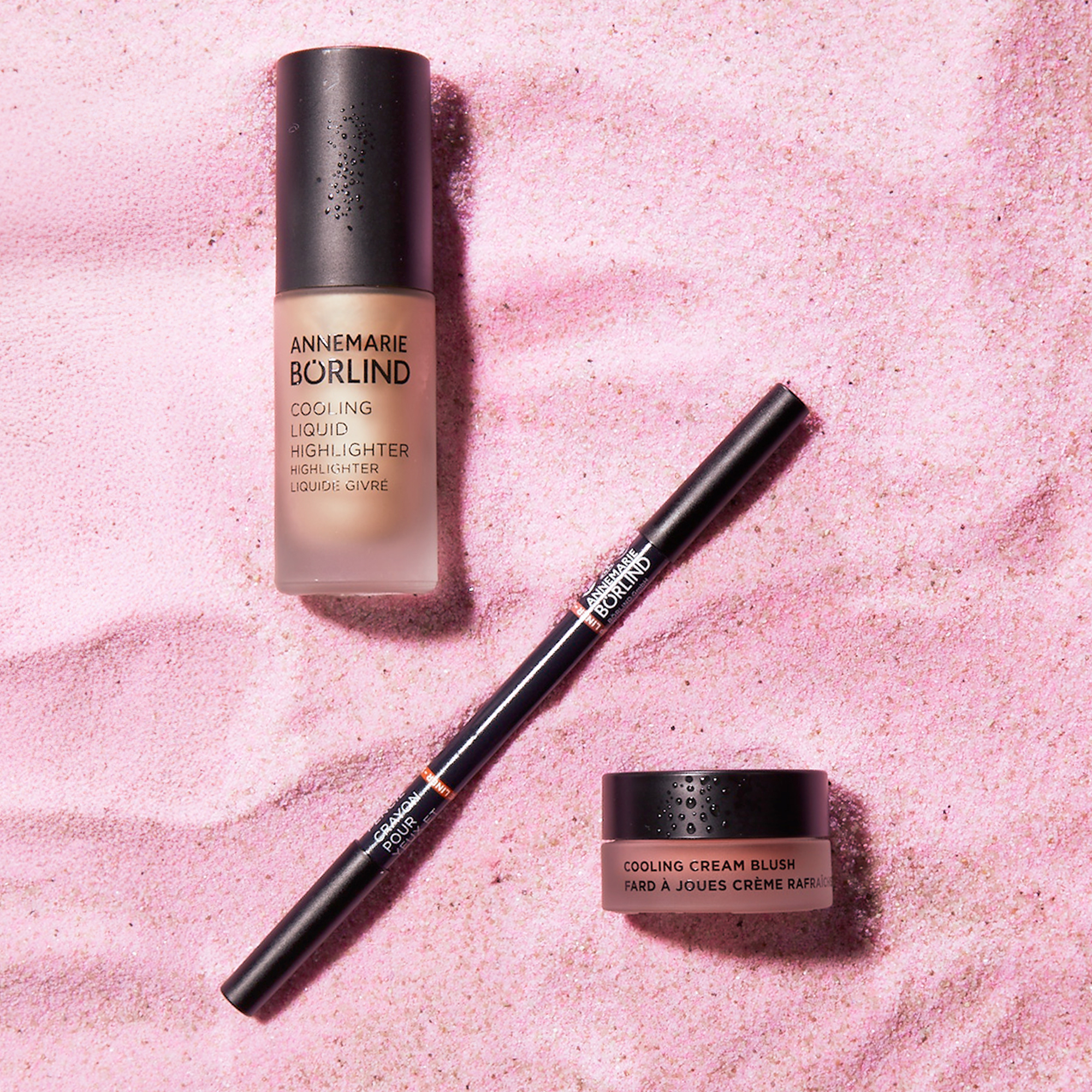 ANNEMARIE BÖRLIND Cooling Liquid Highlighter, Cream Blush und Kajalstift auf rosa Sand