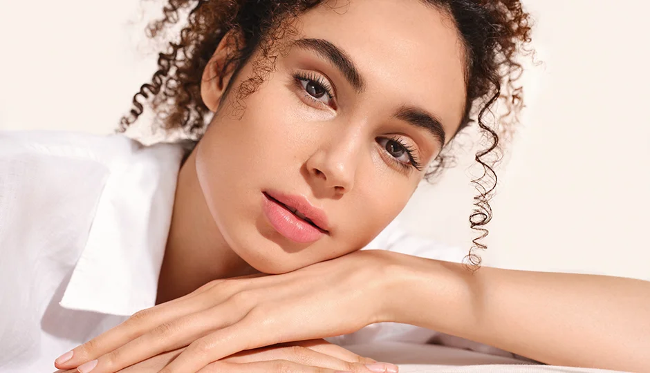 Hautton bestimmen Nahaufnahme einer entspannten Frau mit natürlichem Make-up, die den Kopf auf verschränkten Armen ruht