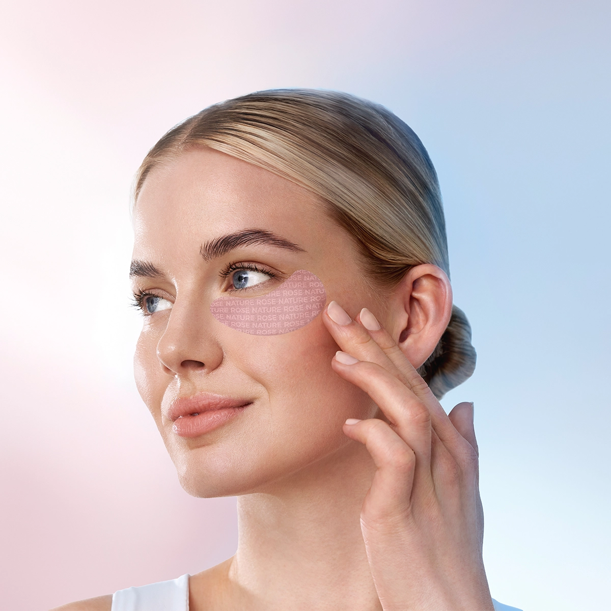 Frau mit glatter Haut berührt rosa kühlende Augenpads von ANNEMARIE BÖRLIND unter dem rechten Auge