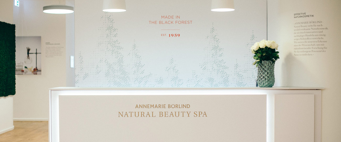 Empfangstresen im ANNE MARIE BÖRLIND NATURAL BEAUTY SPA mit Vase und weißen Rosen, helle moderne Gestaltung