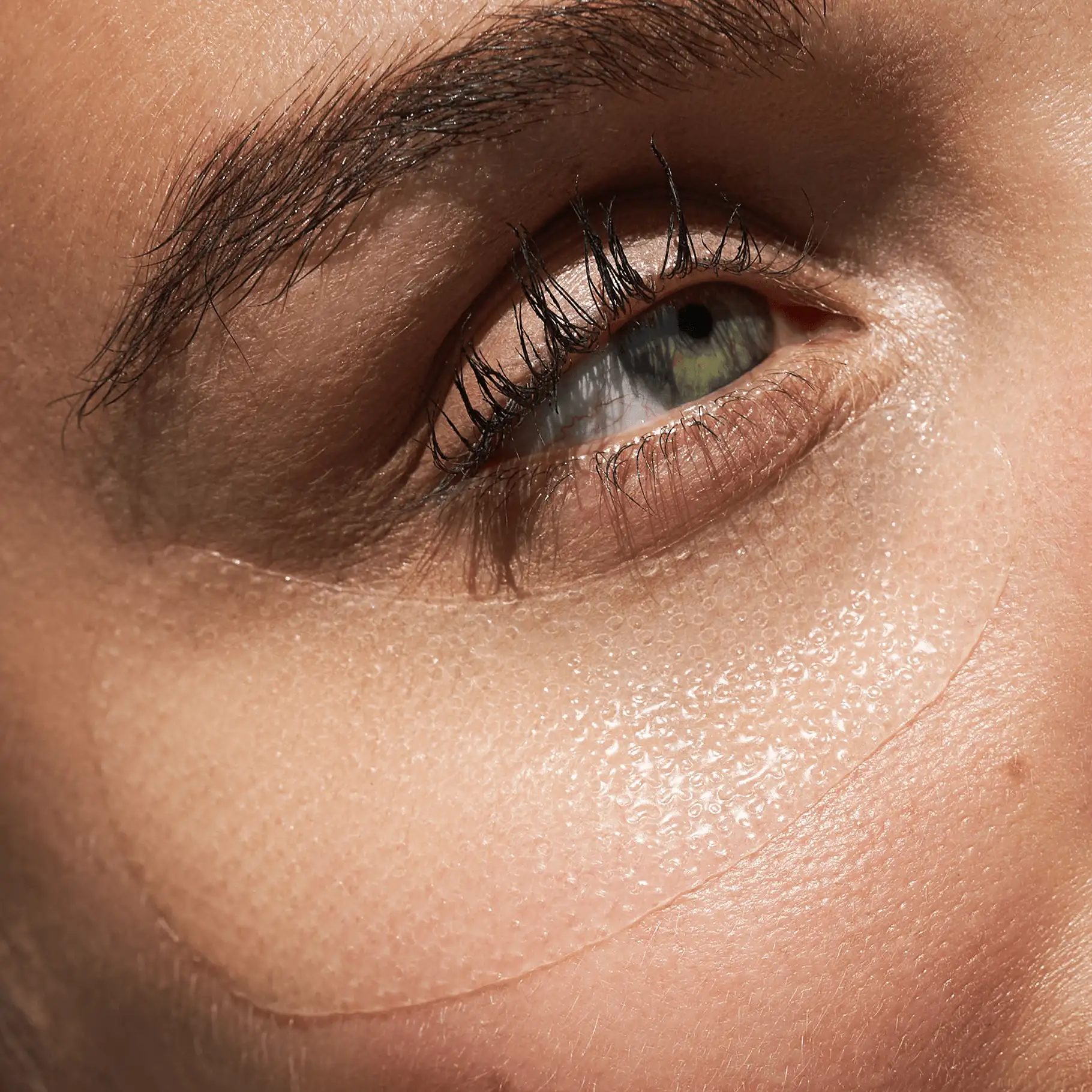 Nahaufnahme eines Auges mit transparentem, feuchtigkeitsspendendem HYALURON Augenpad unter dem Auge