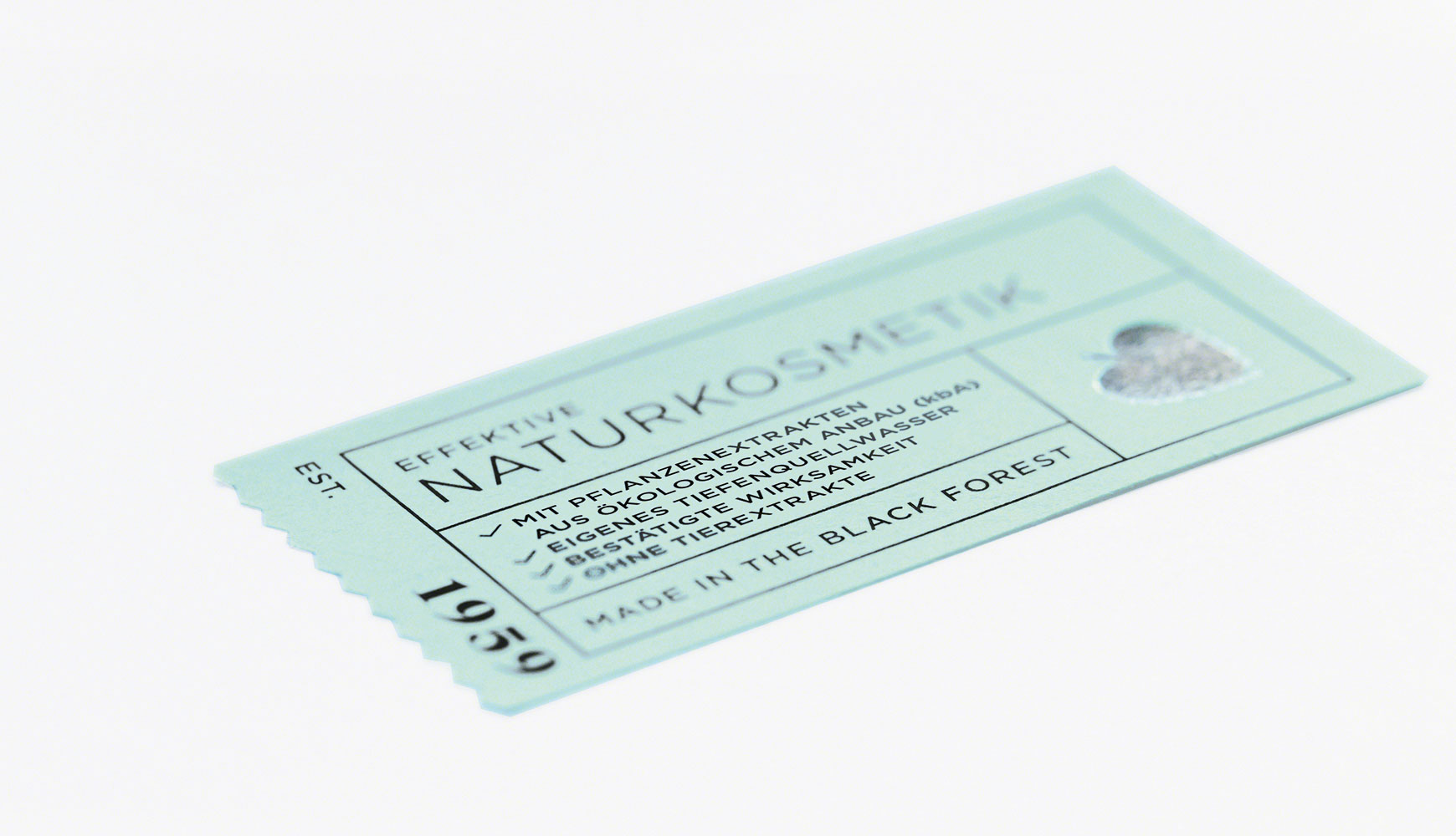 Ticket-ähnliches Etikett mit Text zu Naturkosmetik und pflanzlichen Extrakten auf hellblauem Hintergrund