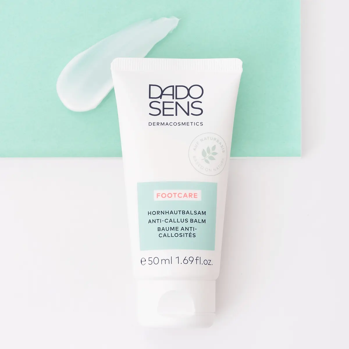 DADO SENS Footcare Hornhautbalsam in 50-ml-Tube mit cremiger Textur auf grünem Hintergrund