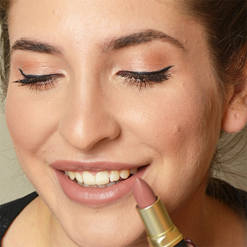 Frau trägt matt-nude Lippenstift auf, Augen mit schwarzem Lidstrich und dezentem Lidschatten geschminkt