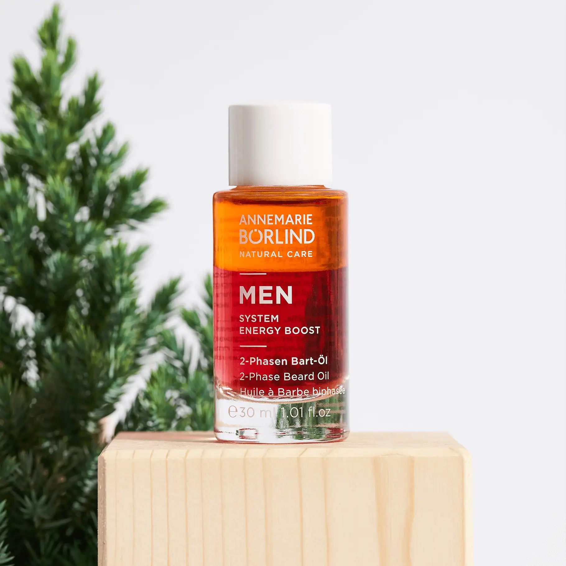 ANNEMARIE BÖRLIND MEN 2-Phasen Bart-Öl in Glasflasche mit weißem Verschluss auf Holzblock vor grünem Hintergrund