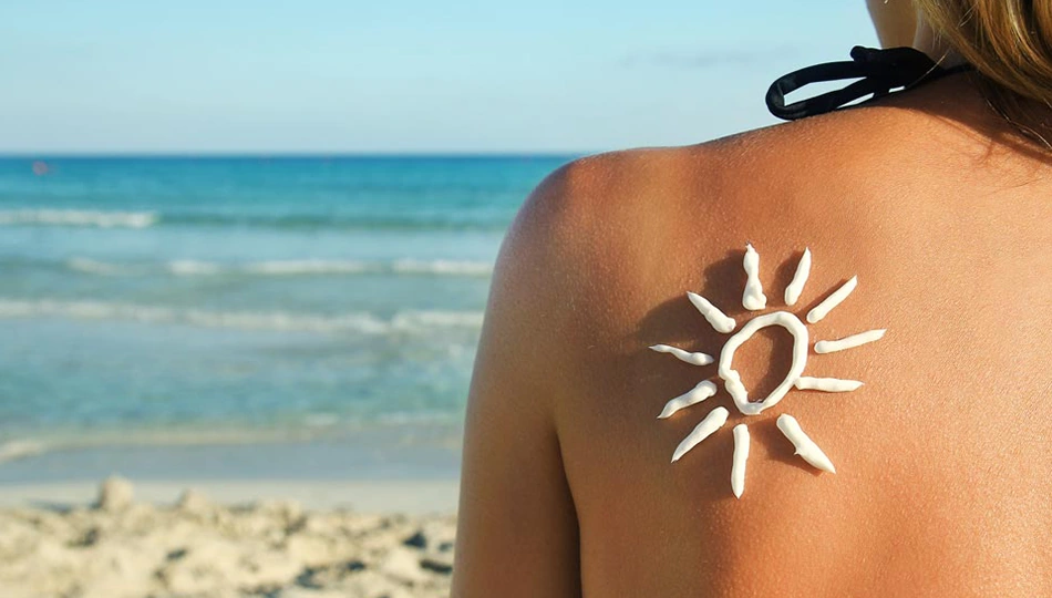 Sonnenschutzmittel Rücken einer Frau am Strand mit aufgemalter Sonne aus Sonnencreme – Symbol für wirksamen Sonnenschutz.