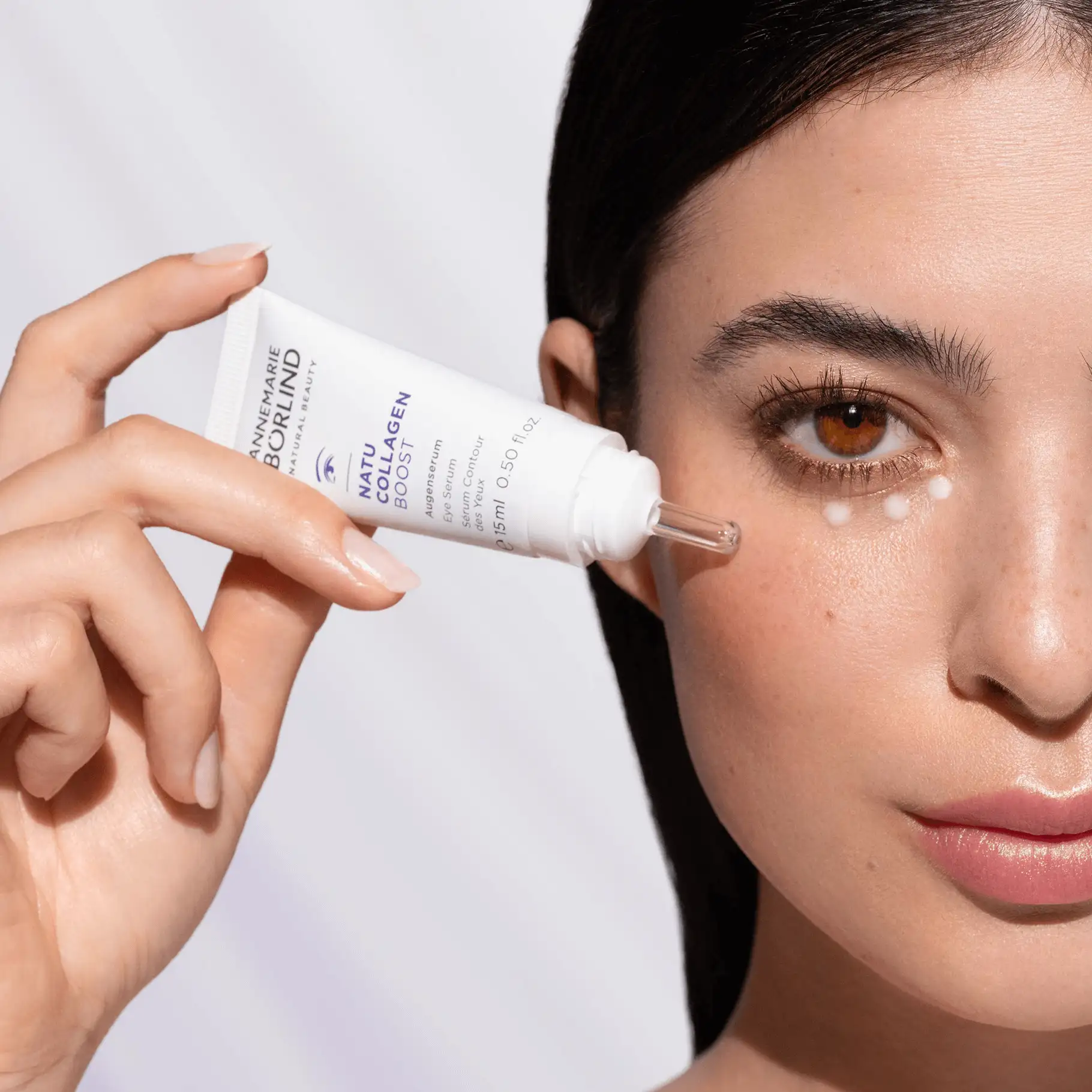 Frau trägt NATU COLLAGEN BOOST Augenserum von ANNEMARIE BÖRLIND mit Pipette unter das Auge auf