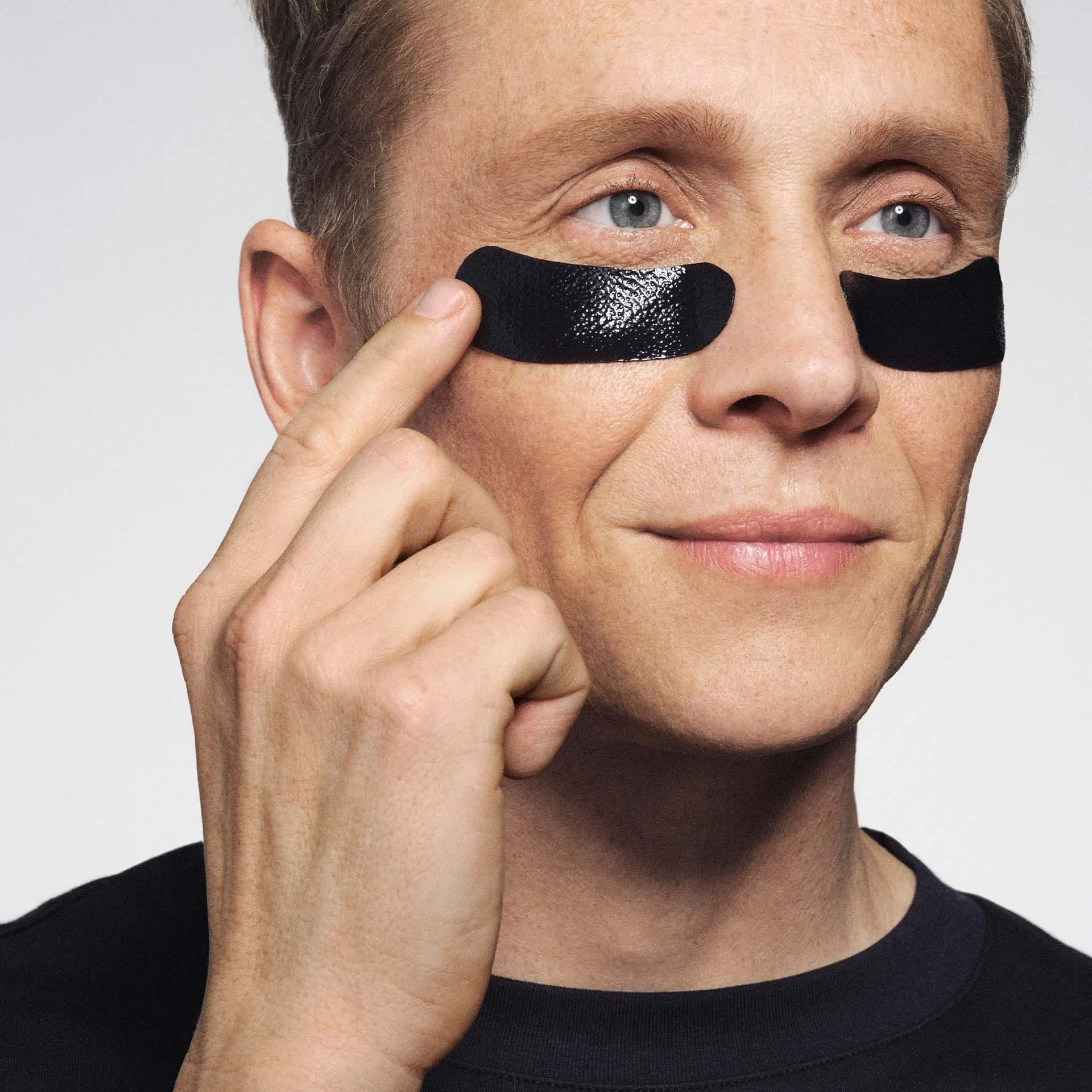 Matthias Schweighöfer bringt schwarze Augenpads unter die Augen auf, Gesichtsausdruck entspannt