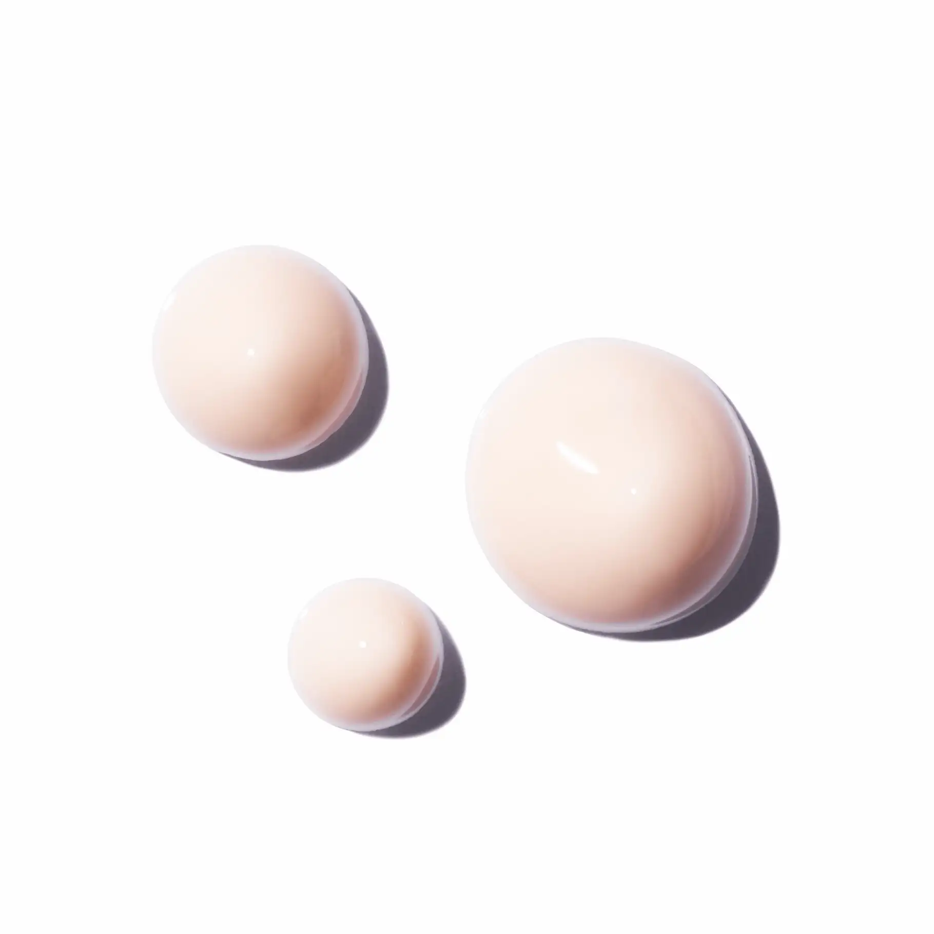 Drei Tropfen hellrosa, cremige Textur auf weißem Hintergrund, glatt und glänzend