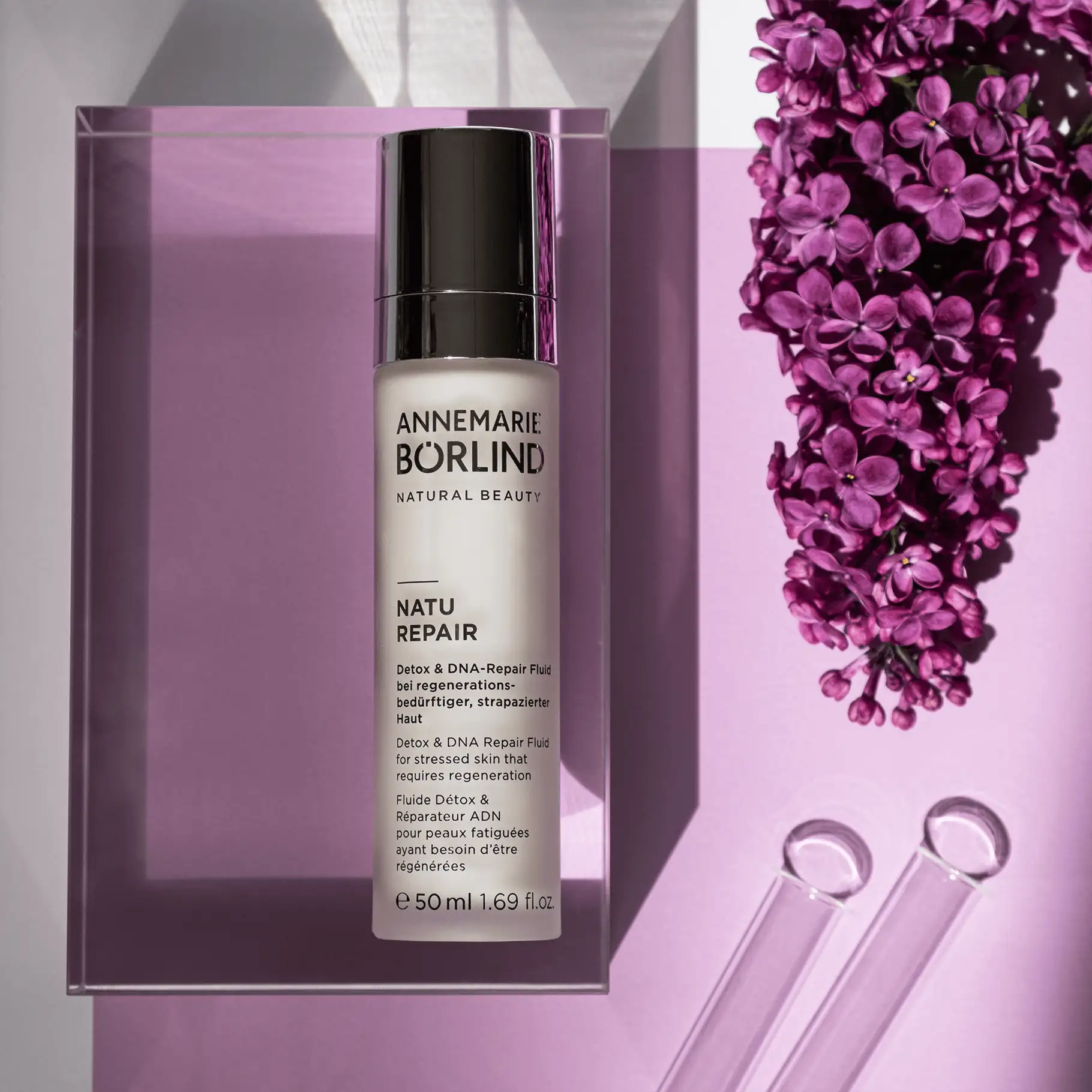 ANNEMARIE BÖRLIND NATU REPAIR Detox & DNA-Repair Fluid mit 50 ml auf lila Untergrund neben lila Blüten