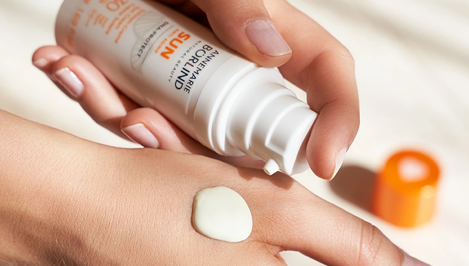 Hand trägt ANNEMARIE BÖRLIND Sonnencreme aus einem Pumpspender auf – UV-Schutz in flüssiger Form.